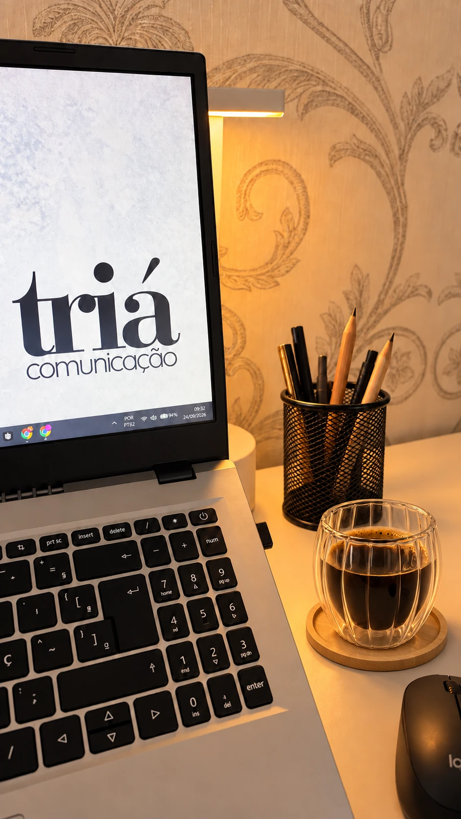 Mesa de trabalho da Triá Comunicação, com a logo no notebook